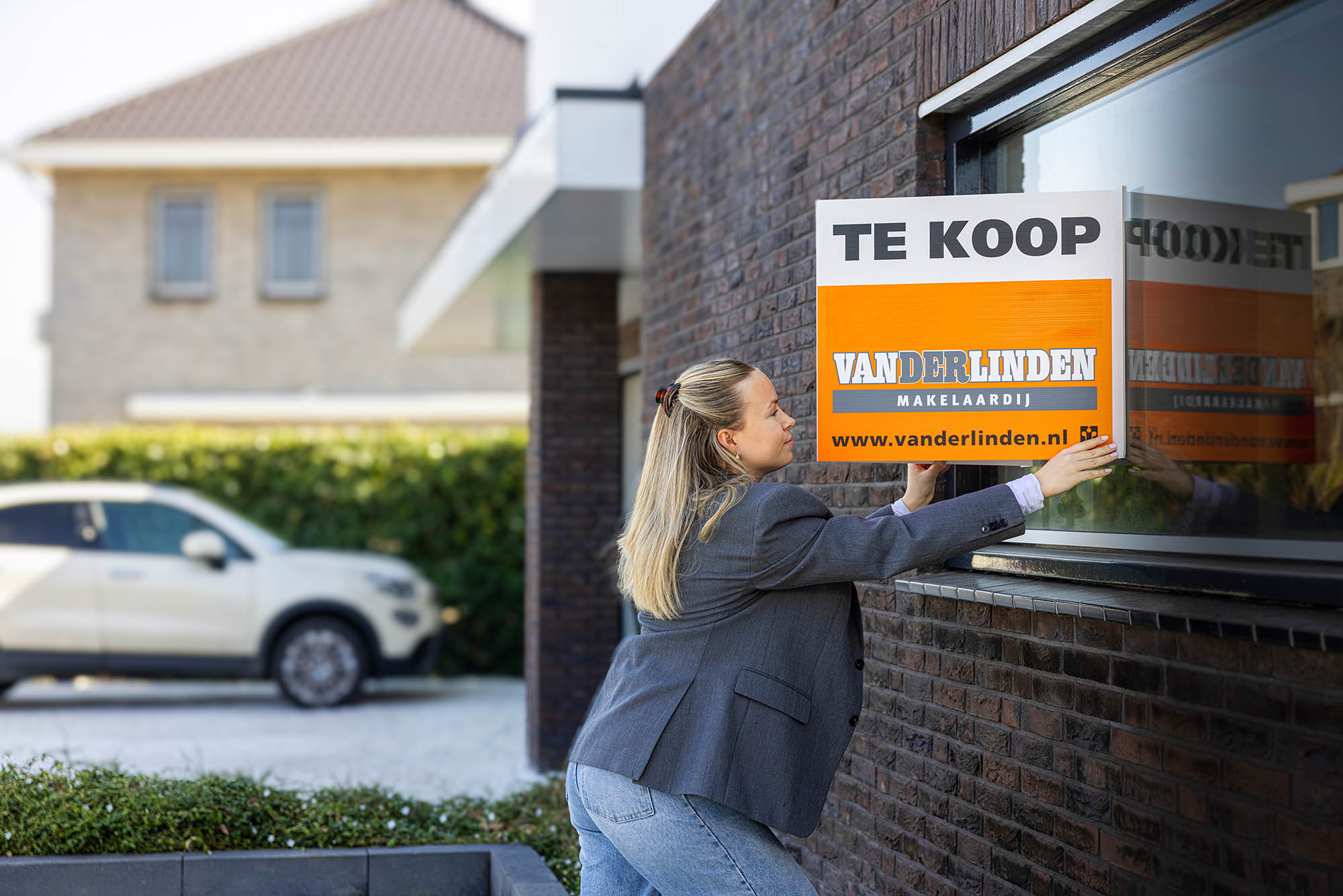 Makelaar aan het werk met te koop / verkocht bord in de arm